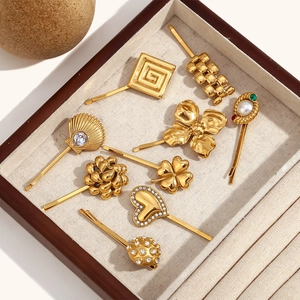 Détail de barrettes dorées à l'or 18K avec perles et strass dans un coffret à bijoux