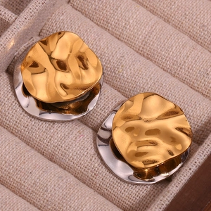 Macro shot of two-tone irregular layered stainless steel round stud earrings in a jewelry box