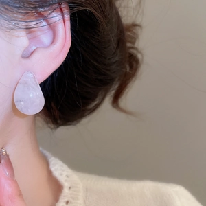 Close-up of translucent pink resin teardrop earring worn by a model in a minimal style