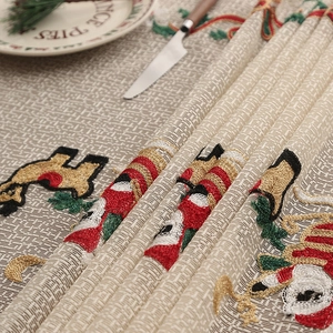 Close-up of festive Christmas table runner with embroidered Santa and reindeer patterns