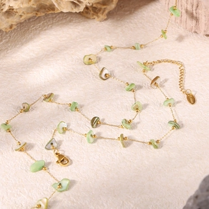 Macro detail of natural light green and beige crushed stones on a gold stainless steel chain