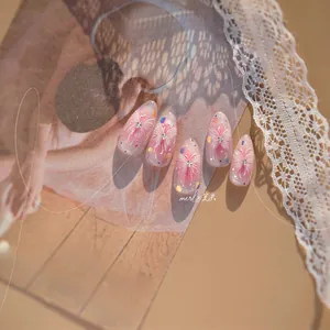 Detailed view of pink gradient press-on nails with white butterfly patterns and silver gems