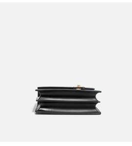 Detailed side view showing gusset folds and black leather texture of the square bag
