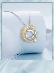 Macro shot of silver meteor necklace with gold crescent moon and zircons on blue stand