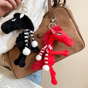 Close-up of black and red flocked horse charms with striped scarves on a brown suede bag