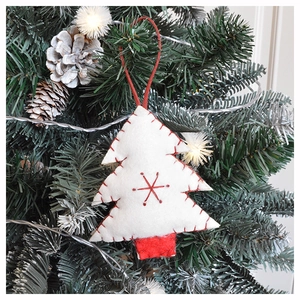 Christmas tree felt ornament with red stitching and snowflake pattern hanging on a tree