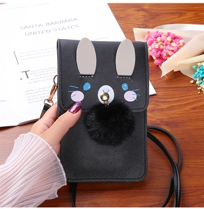Detail of black touch screen crossbody bag with cute bunny ears and plush ball charm