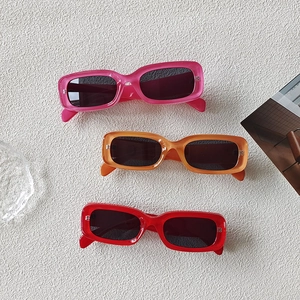 Three rectangle frame sunglasses in pink orange and red colors on a white textured background