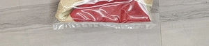 Close-up of red and beige textured Christmas gift bag fabric in clear packaging