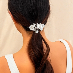 Close-up of a silver liquid metal hair clip with irregular ruffled texture on hair