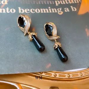 Detail of vintage gold-plated drop earrings with black enamel and micro-pave crystals