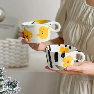 Hand-painted ceramic mugs with cute pear and floral patterns held in a cozy home setting