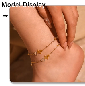 Macro shot of gold anklet featuring a cubic zirconia heart and heartbeat pulse wave design
