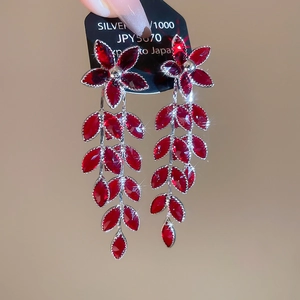 Makroaufnahme von roten Kristall-Blumenohrringen mit silbernen Quasten und Blatt-Design