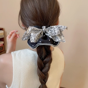 Chouchou noeud en tissu à pois et cachemire montré sur une coiffure tressée chic