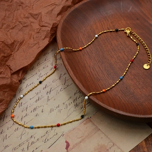 Detail of colorful enamel beads on a gold stainless steel chain with lobster clasp