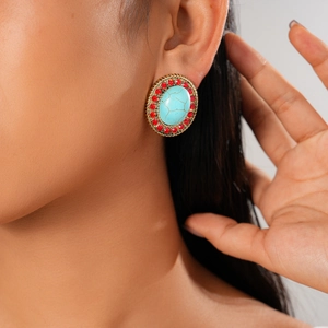Close-up of bohemian oval turquoise earring with red rhinestones on gold metal base