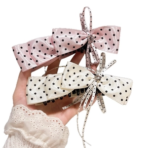 Main tenant des jolies barrettes à cheveux en satin rose et crème à nœuds à pois