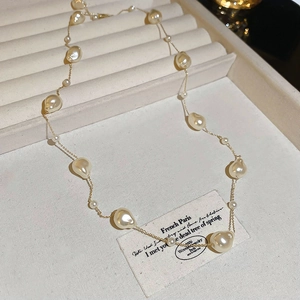 Macro detail of Baroque pearls on a thin gold plated chain over a textured tray