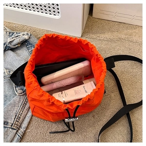 Detailed interior of orange drawstring bucket bag showing large capacity with personal items