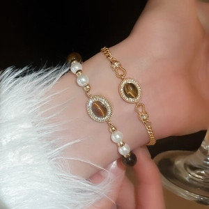 Détail de bracelets vintage dorés avec pierres œil de chat et perles au poignet