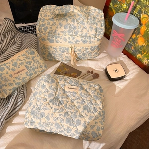 Detailed set of blue floral quilted cosmetic bags in three sizes for travel storage