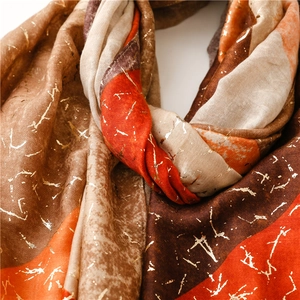 Detailed close-up of soft winter shawl with orange and brown blocks and golden foil patterns