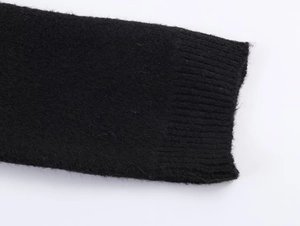 Détail du poignet et de l'ourlet en maille noire montrant la texture du tissage
