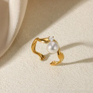 Macro detail of wave-shaped gold ring with white pearl and sparkling zircon stone