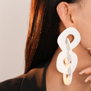 Gros plan d'un mannequin portant de grandes boucles d'oreilles blanches en acrylique