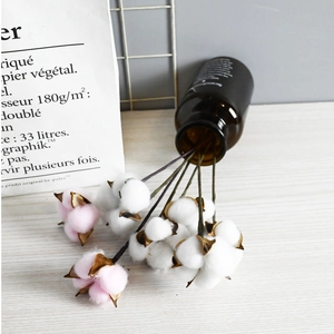 Detailed view of pink and white artificial cotton flower stems in a glass vase decor