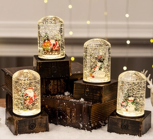Close-up of glowing Christmas snow globes with Santa and snowman figures on vintage bases