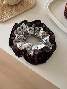 Gros plan d'un chouchou floral avec fleurs rouges et bordure en dentelle blanche