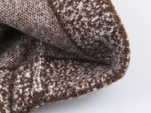Close-up of thick beige and brown knit fabric showing texture and soft wool fibers