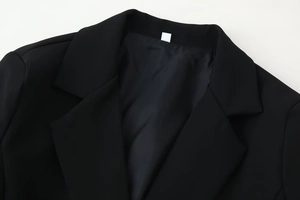 Detailed view of the notch lapel and fabric texture on a black women's tailored blazer
