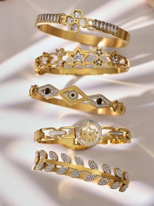 Close-up of assorted gold-plated bangles with zircon clover and evil eye details