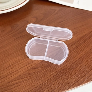 Detailed view of portable transparent jewelry box with two compartments on a wooden table