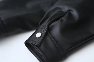 Detail of black PU leather jacket cuff with silver metal button and stitching