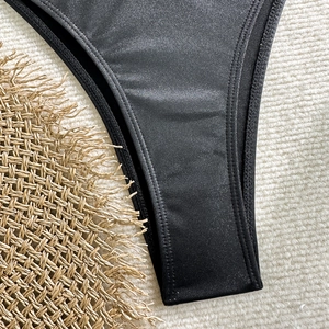 Close-up of black bikini bottoms featuring premium satin finish and double-needle stitching
