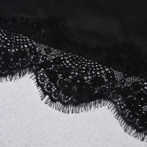 Close-up of black floral lace trim and smooth satin fabric on camisole hem