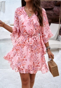 Close-up of pink floral dress with V-neck, bell sleeves and waist tie at poolside