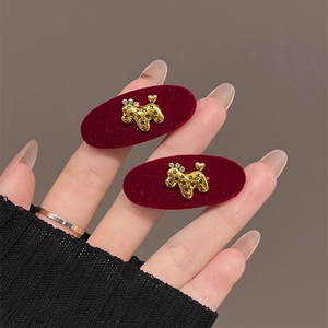 Handheld red velvet hair clip set with golden rhinestone-encrusted dog design
