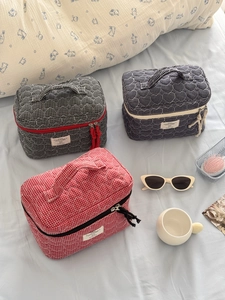 Detailed view of quilted heart pattern vanity bags in red, black and navy blue