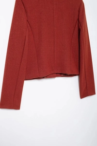 Gros plan détaillé sur la texture du tissu en tweed terracotta et la manche de la veste