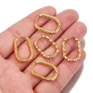 Detailed close-up of five textured gold rectangular earring findings on a person's palm