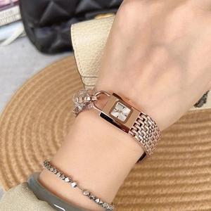 Close-up of rose gold square watch with chain strap on wrist with lifestyle background