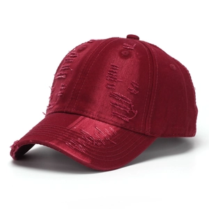 Close-up of distressed ripped details on a vintage burgundy washed denim baseball cap