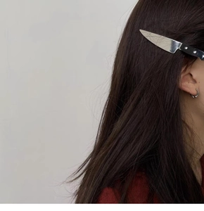 Detail view of a realistic dagger-shaped hair clip worn on a side profile with dark hair