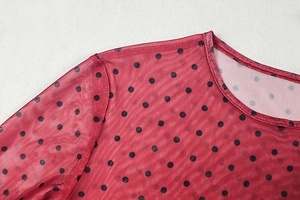 Detail view of red sheer mesh fabric with black polka dots and fine stitching on the collar