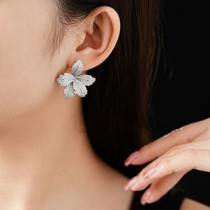 Detailaufnahme von silbernen Blumenohrringen mit Zirkonia am Ohr eines Models
